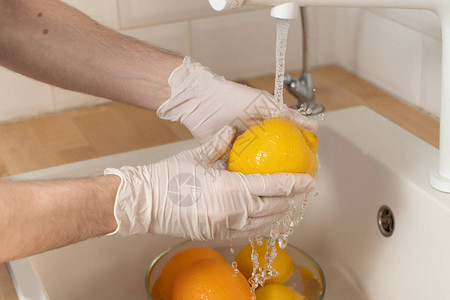 一名男子用手套洗柠檬和洗涤剂图片
