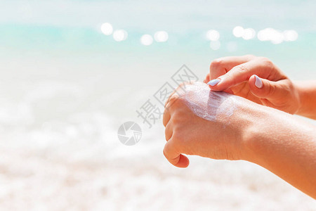 穿泳衣的女人用手指在海面背景用太阳霜图片
