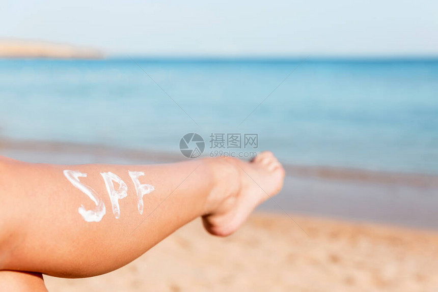 在海滩上用日霜做成的雌腿太阳保护因素的概图片