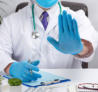 穿着白色医疗大衣的医生坐在棕色皮椅的桌子上图片