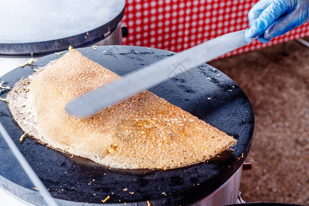 在食品市场上做煎饼一只手在金属网格上户外图片