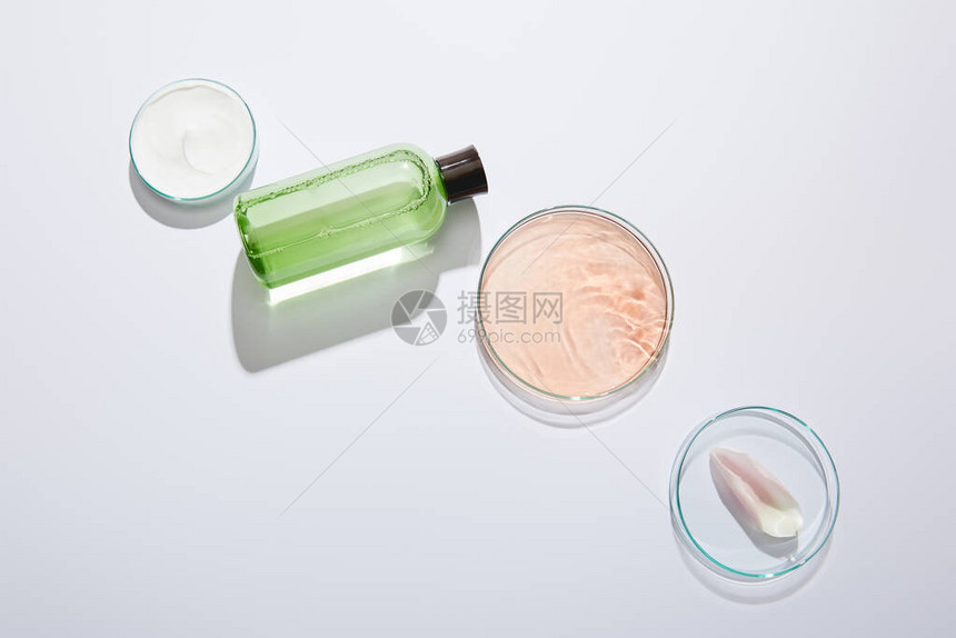平铺有实验室玻璃器件装绿色液体的化妆瓶化妆奶油罐和图片