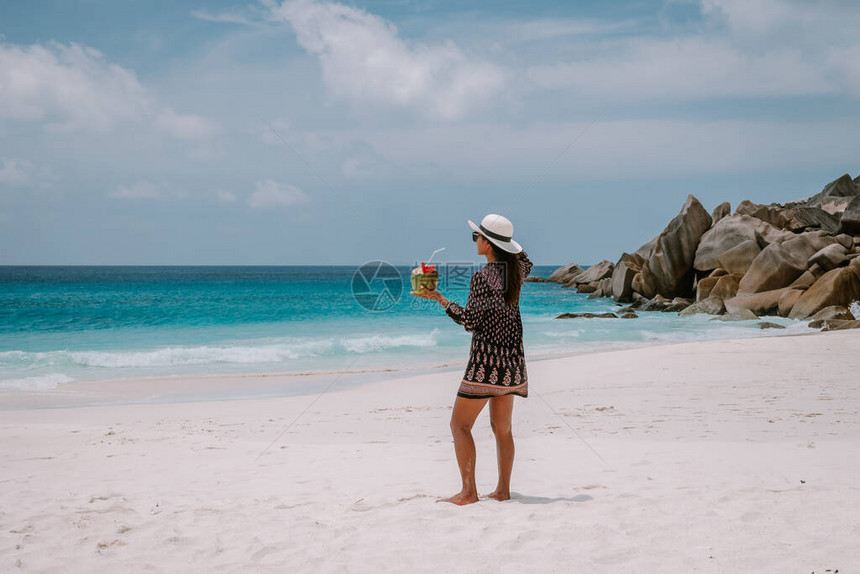 年轻的中年妇女在塞舌尔热带岛屿度假时在海滩上散步图片