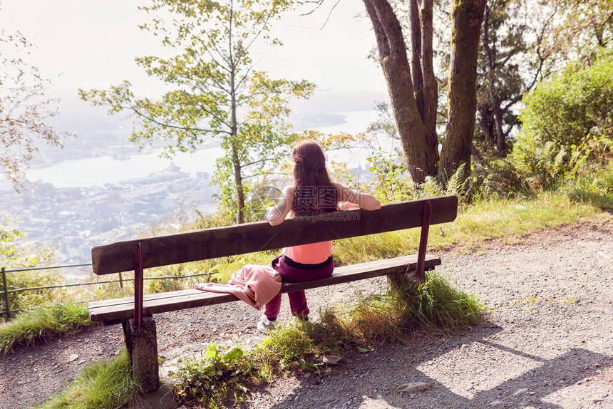 女孩坐在森林的长椅上图片