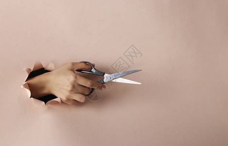 女手握剪刀穿透粉色纸圆图片