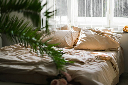 晨光照在床上皱巴的床上用品靠近窗户的空床卧室内部现代室图片