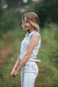 一个年轻的金发女孩站在林间小路上图片