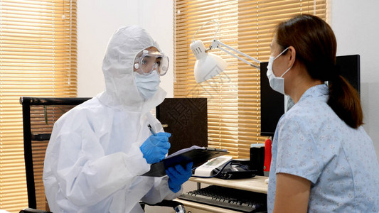身戴面罩和眼镜检查受感染女患者健康状况的亚洲保护个人防护设备图片