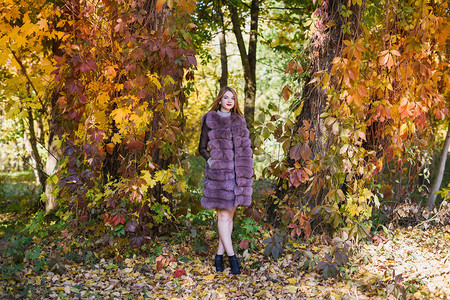 时装女人秋天公园穿毛皮大衣的微笑女孩图片