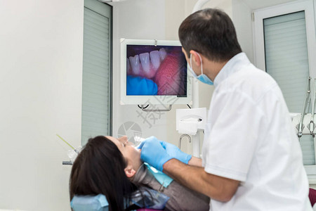 牙科医生用相机检查病人的牙齿图片