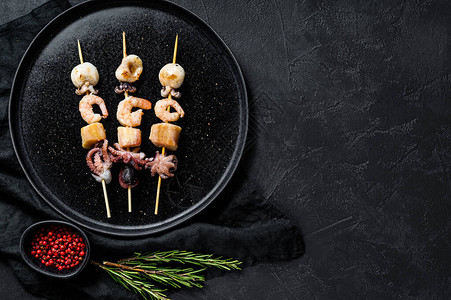 木串配虾章鱼鱿鱼和贻贝烤肉串配海鲜黑色背景顶视图片