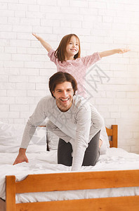 坐在她父亲背上模仿在床上玩耍图片