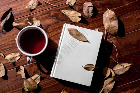白书和咖啡杯周围有树叶背景图片