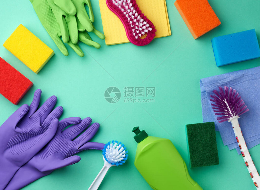 用于清洁的橡胶手套多色海绵刷子和绿色背景的绿色塑料瓶中的清洁液文图片