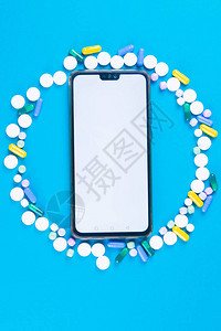 大量药片围绕着蓝色背景的电话制药行业的高分辨率图像移动应用具有清晰图片