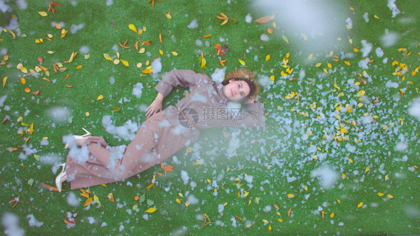 草地上的女孩顶视图下雪时女孩躺在黄图片