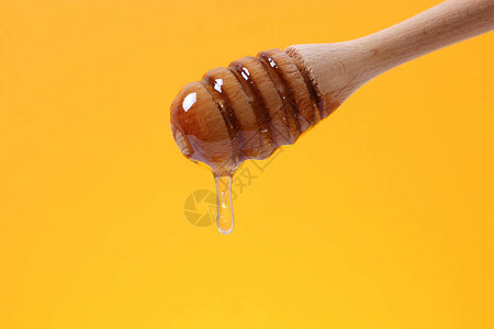 蜂蜜从木勺里滴下来用彩色明图片