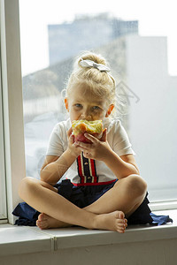 金发小女孩坐在家里的窗台上图片