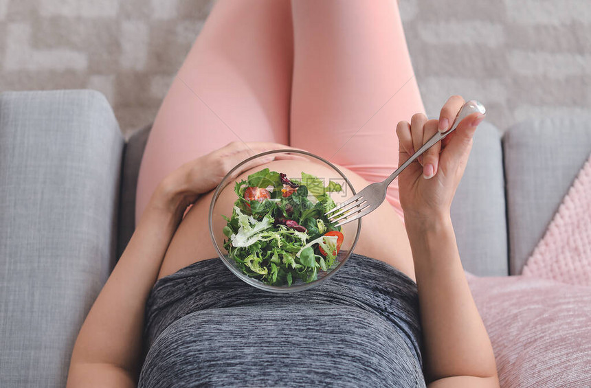 美丽的孕妇在家吃健康沙拉图片