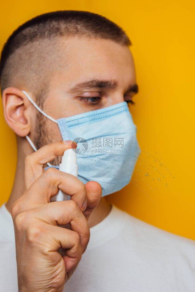 黄色背景上戴着呼吸器的年轻医生的画像用防腐剂消毒冠状的概念防止细菌和疾图片