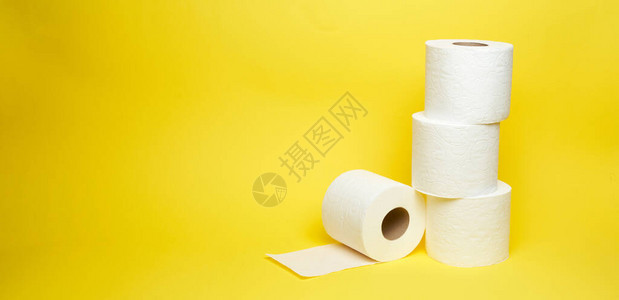 黄色背景上白色卫生纸卷的广角镜头图片