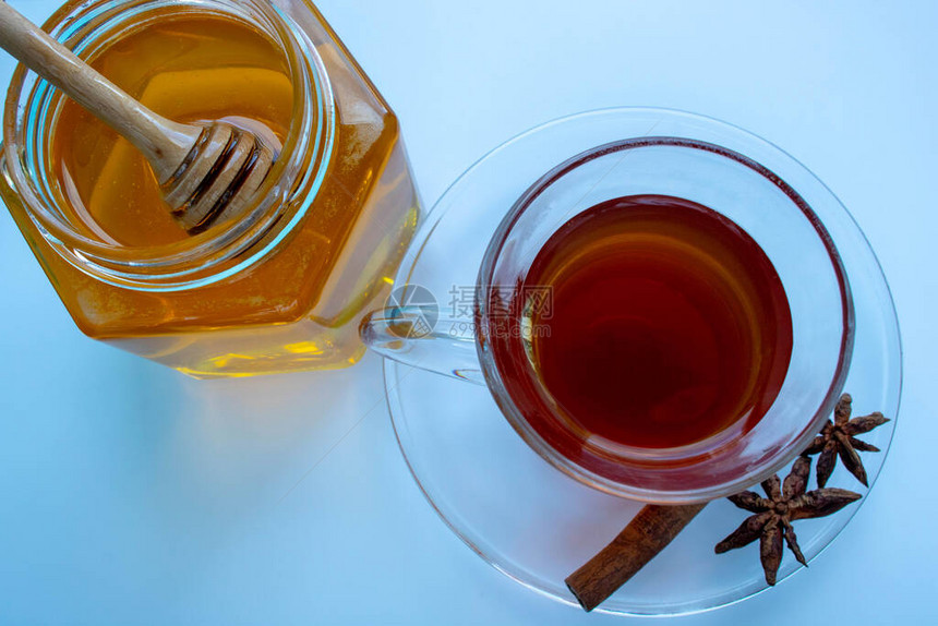 杯子里的黑茶蜂蜜在玻璃罐里用木勺子图片