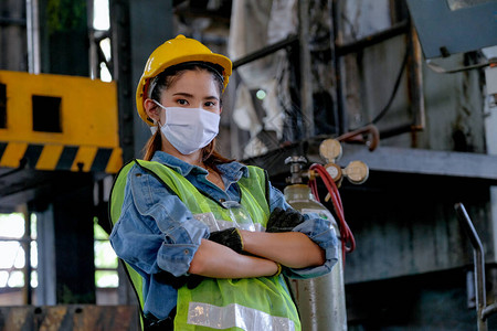 工厂女工或有卫生面具的技工以大机器作为背景图片