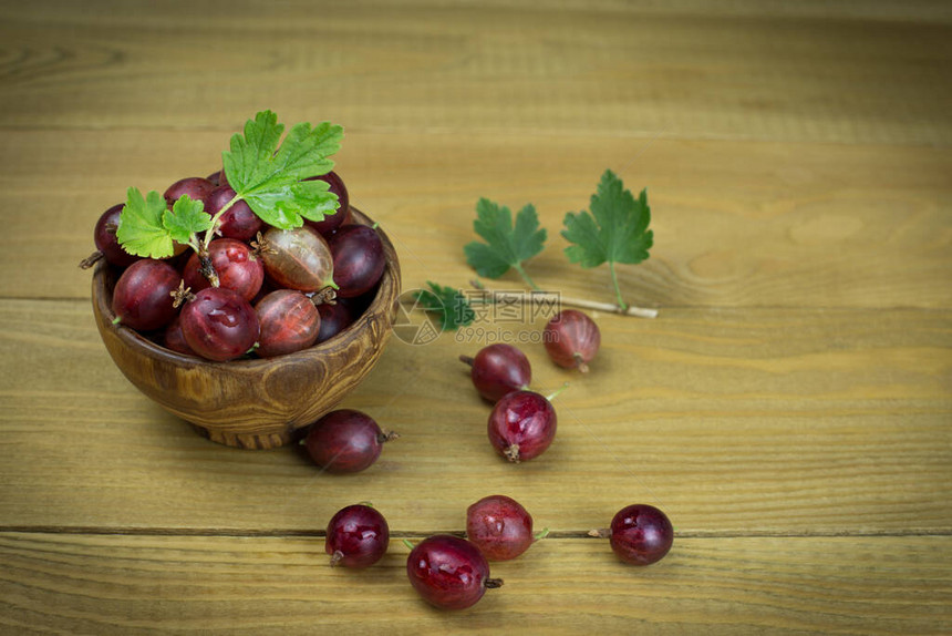 红莓果子在一个木碗里在木质背景上是图片
