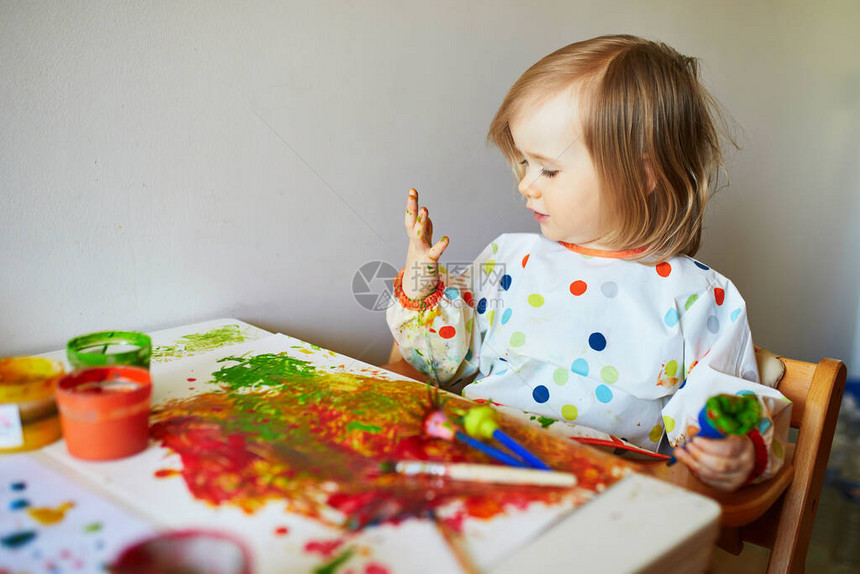 可爱的小女孩在家中幼儿园或学龄前用刷子和手指绘画图片