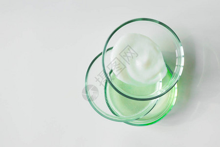 玻璃培养皿与白色背景的各种化妆品图片
