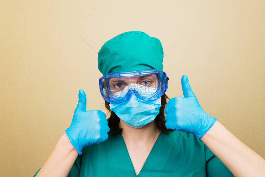 穿绿色西装戴蓝面罩手套和戴黄色保护眼镜的女医生图片