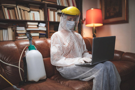 戴着防护抗面具和制服的女在家使用笔记本电脑工作阅读新闻上网图片