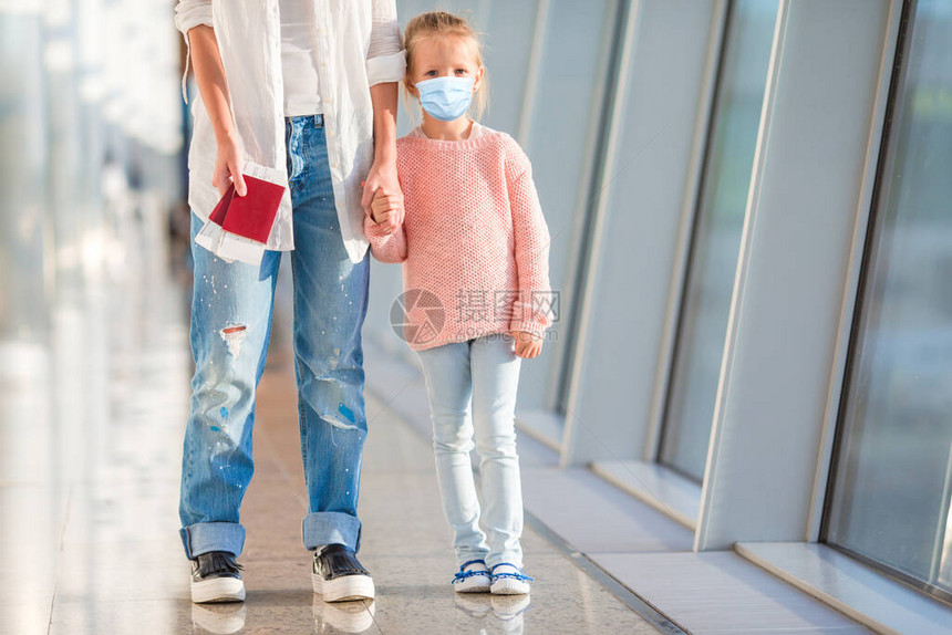 在国际机场戴着外科口罩面的可爱小孩母亲和小女儿在机场候机楼有登图片