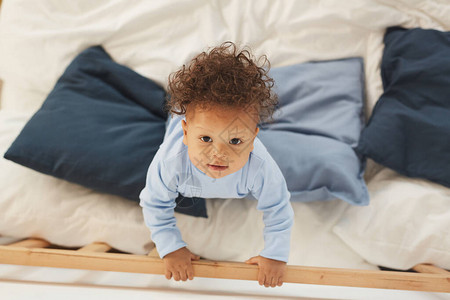 婴儿男孩在床上玩耍时仰望的顶端风图片