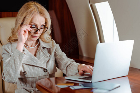 在使用笔记本电脑接近信用卡和护照机票在飞机上摆着的机票时图片