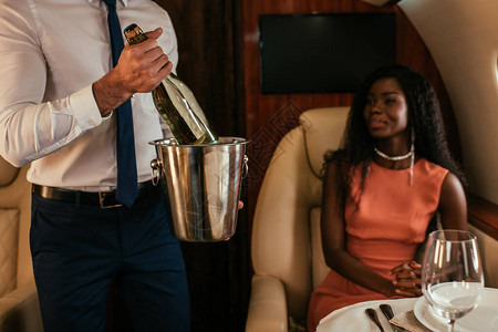 持香槟桶和瓶子的空姐在优雅的美籍非洲妇女图片