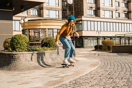 滑板女子在城市牛仔服的溜冰女孩在广场上骑着她的滑板运动女子滑板运动员建立在背景上休闲活动城市背景图片