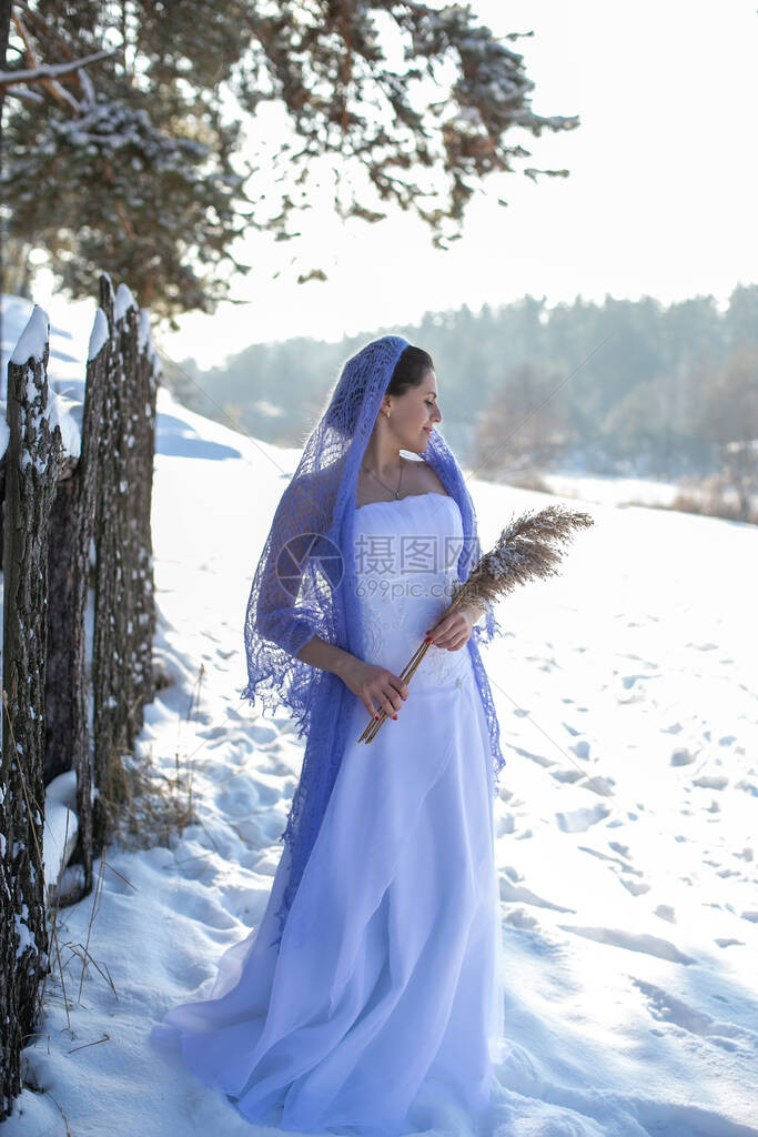穿着白色长裙的漂亮女孩站在冬天风景的背景下图片