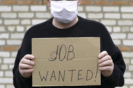 概念失业和冠状一个戴着医用卫生面具的男人拿着一块纸板图片