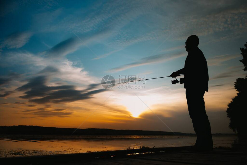 钓鱼日落时旋转渔夫的剪影图片