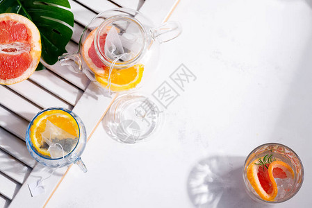 玻璃和一壶冷天然夏季自制茶饮料和白色背景上的柑橘片图片