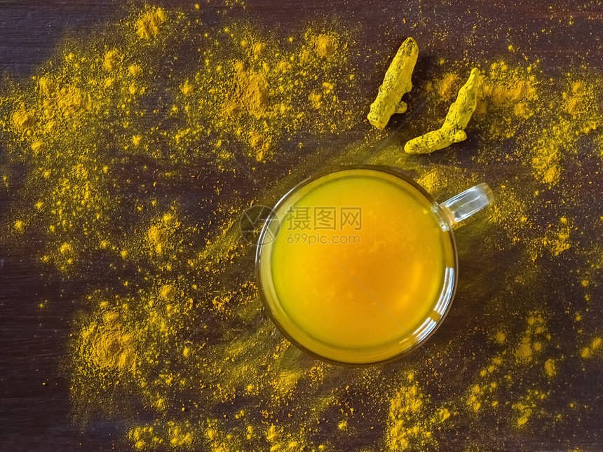 在棕色的桌子上放着姜黄粉和姜黄根的凉茶预防抗感染阿育吠陀治疗的香料图片