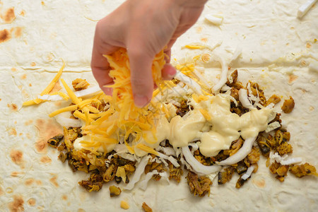 妇女做饭时在皮塔面包中洒上奶酪片的油炸图片