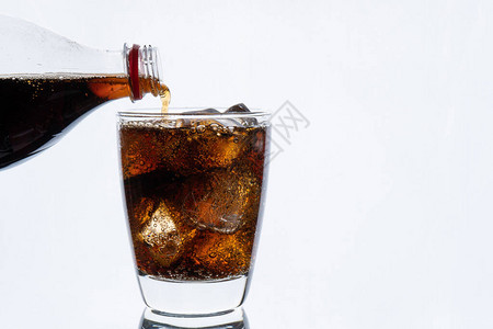 冷饮从瓶中倒苏打水加冰的可乐和热饮料以及白底孤图片