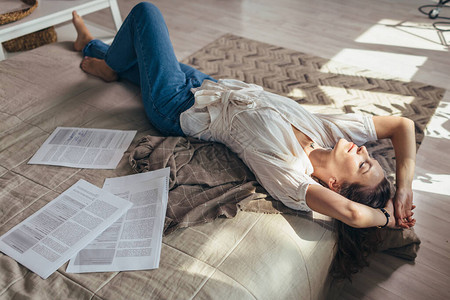 家里的一位年轻女子躺在床上休息的报纸图片