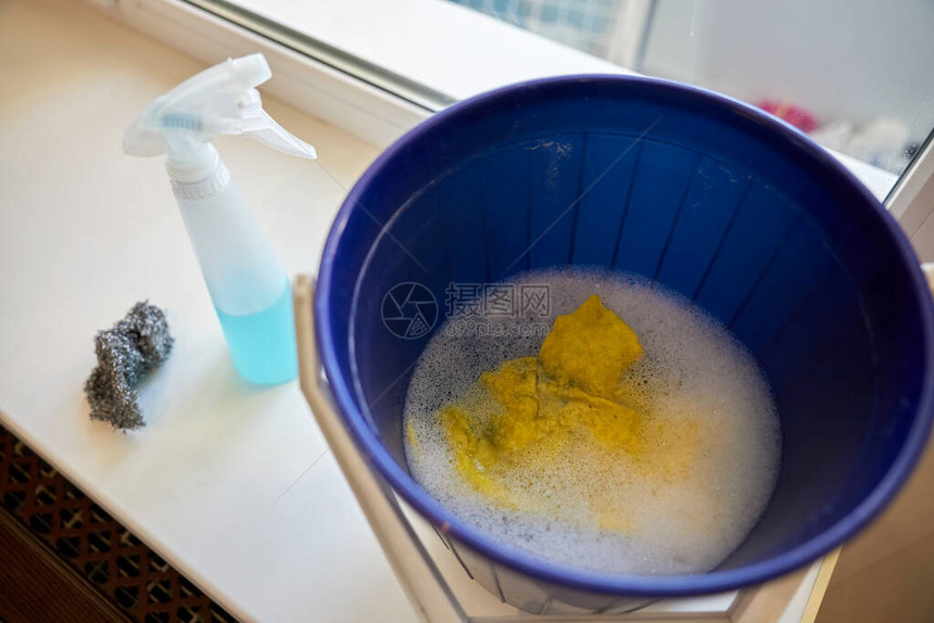 一桶肥皂水一块抹布和一个用于清洗窗户的喷雾瓶图片