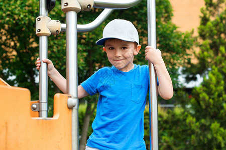 运动童装素材可爱的小男孩在户外操场上攀爬快乐健康的童年戴着帽子的时尚孩子童装时尚暑假孩子们在户外积极休闲快乐的男孩背景