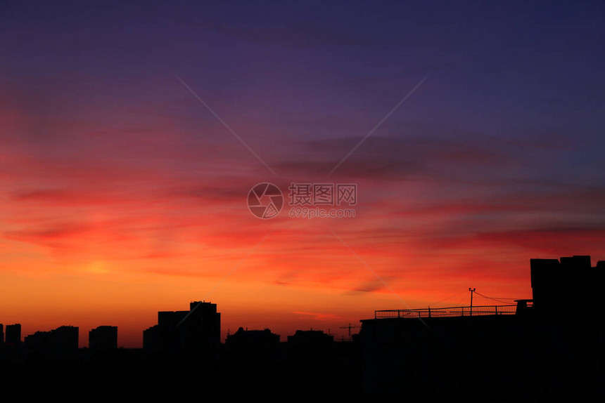 晚上在城市上空的明亮的橙色日落城市建筑的高层建筑明亮的灯光建筑城市起重机剪影在建筑图片