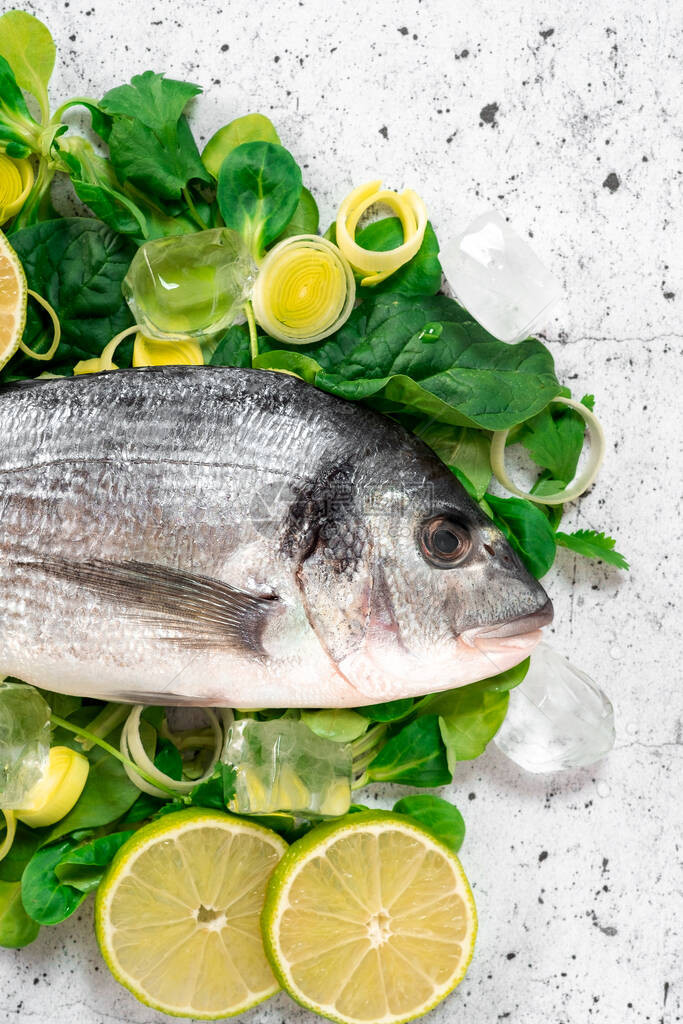 绿色香草和香料上的新鲜海鱼多拉准备在白色背景下烹饪健康食品的图片