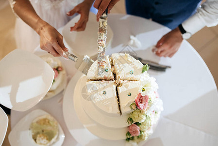 新娘和新郎在婚宴上切他们时尚的婚礼蛋糕新婚夫妇拿着刀一图片